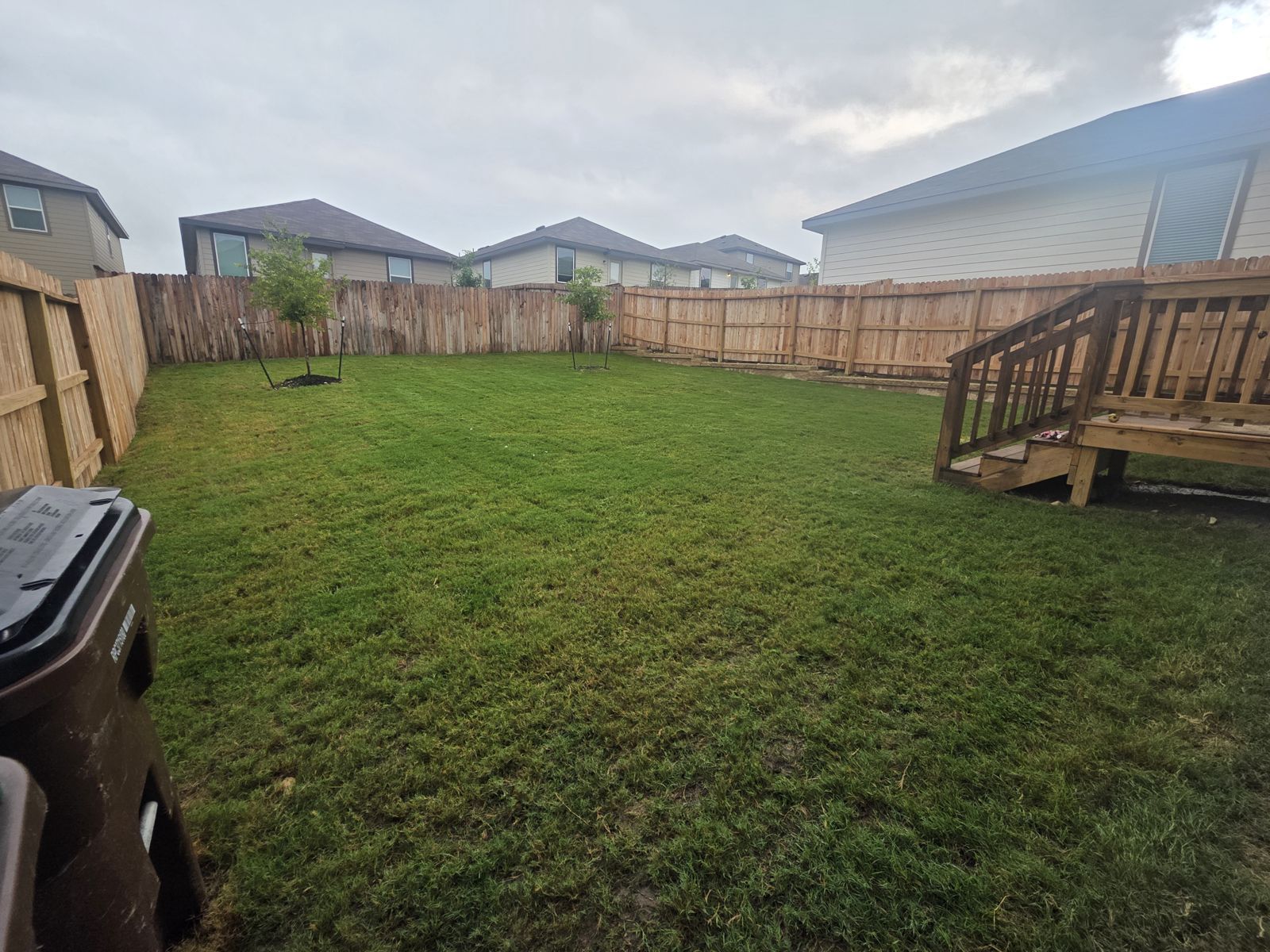 Freshly mowed backyard lawn with a wood privacy fence and deck